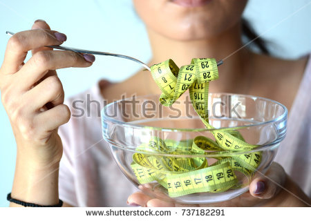 stock-photo-young-woman-on-diet-eating-a-yellow-measurement-tape-from-a-transparent-bowl-abstract-image-737182291.jpg