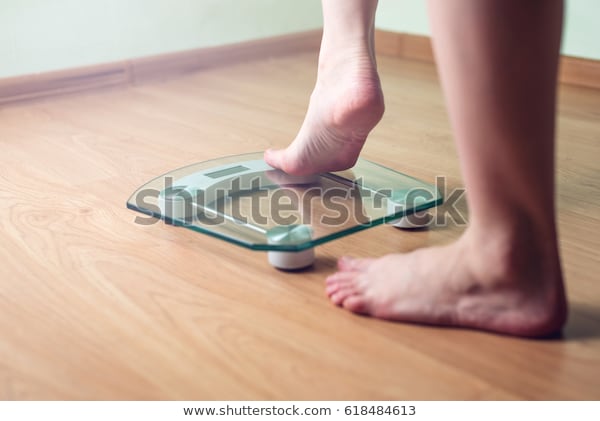 female-feet-standing-on-electronic-600w-618484613.jpg