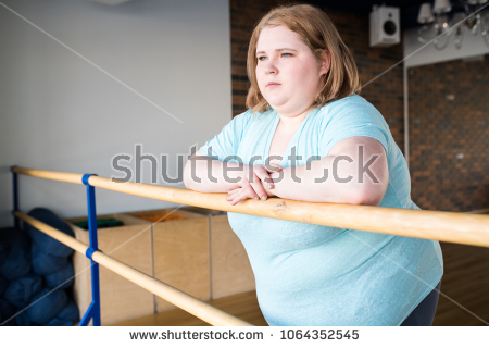 stock-photo-waist-up-portrait-of-obese-young-woman-standing-at-bar-in-dance-class-looking-pensively-at-window-1064352545.jpg